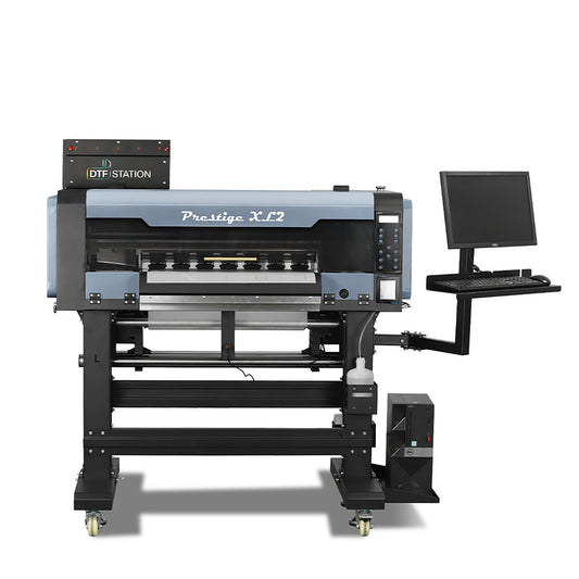 Front-facing view of the Prestige XL2 24" production roll-to-roll DTF printer, featuring an integrated workstation with a monitor mount and dual Epson i3200 printheads.