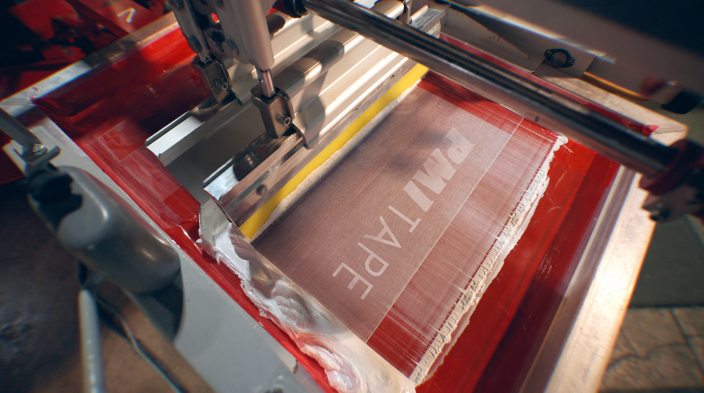 Close-up of a machine applying tape to a surface with 'TAPE' text visible.