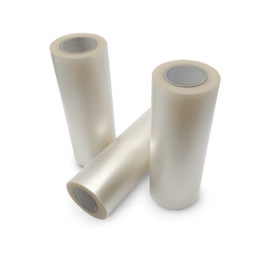 Three rolls of clear plastic film standing upright on a white background, with one roll lying diagonally in front.