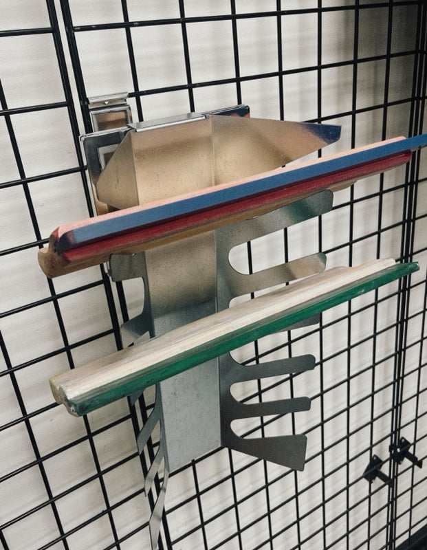 Wall-mounted aluminum squeegee rack holding six screen printing squeegees.