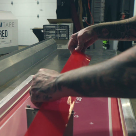 Video showing a person applying PMI Red Screen Printers Tape to the edges of a screen printing frame in a shop setting, demonstrating its easy application and secure seal.