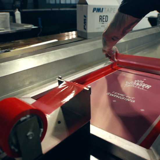 Demonstration video of PMI Red Screen Printers Tape being applied to a screen printing frame, showing its soft adhesive creating a leak-proof seal on the mesh.
